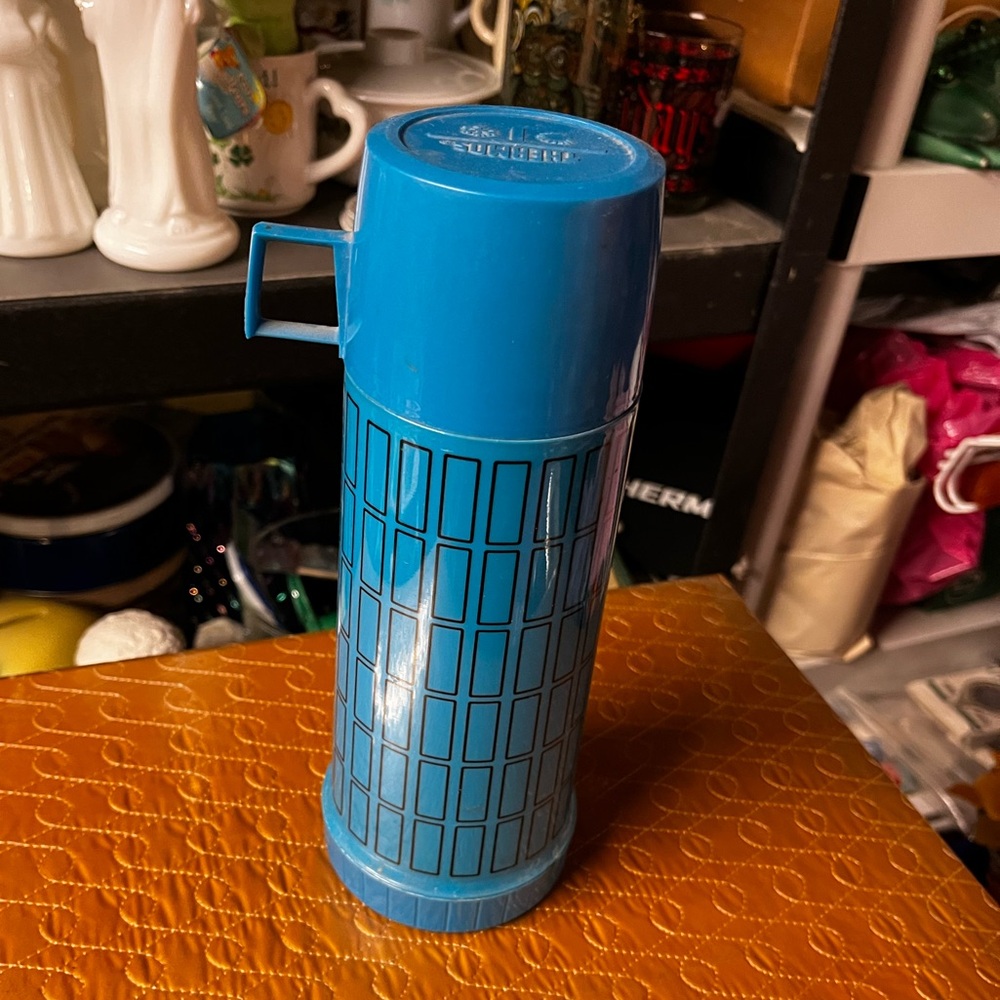 Vintage blue thermos with black rectangular designs.